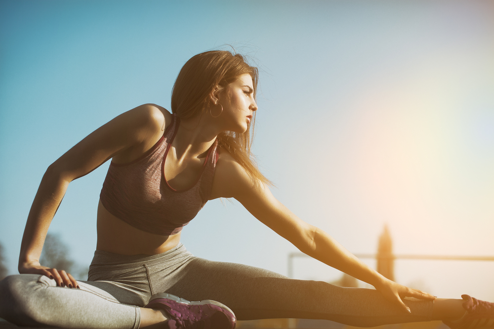 A man and woman wearing athletic gear give each other a high-five outdoors - Chiropractor Langhorne PA